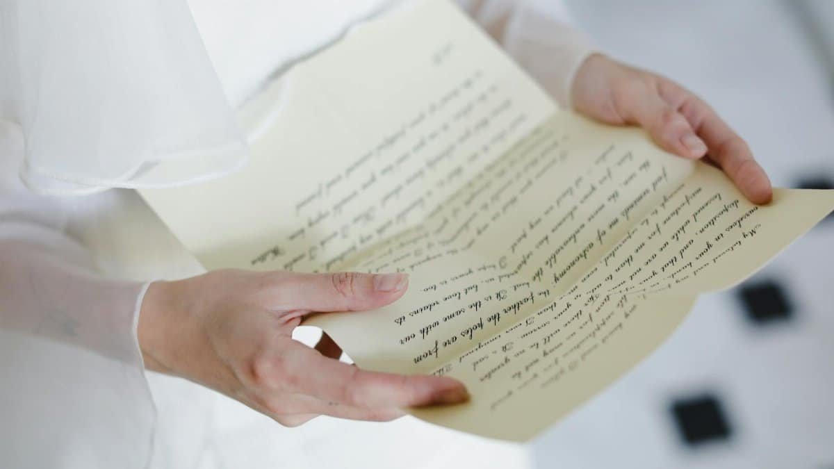 Close-up of hands delicately holding a handwritten letter with calligraphy.