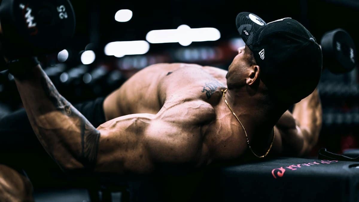 Focused athlete lifting dumbbells in an indoor gym environment, showcasing strength and dedication.