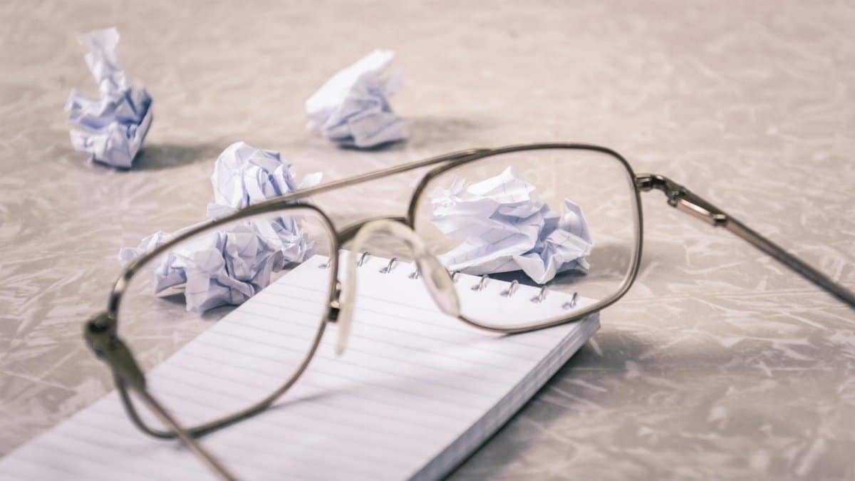 Eyeglasses and crumpled paper on notepad, symbolizing creative brainstorming process.