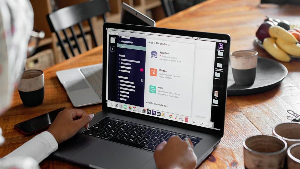 Person using laptop in cozy workspace with coffee and fruits. Perfect for remote work themes.