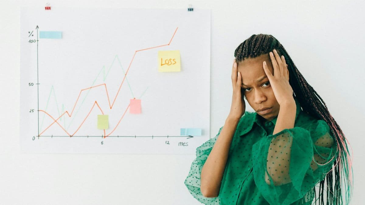 Businesswoman analyzing financial chart with loss noted, expressing stress.