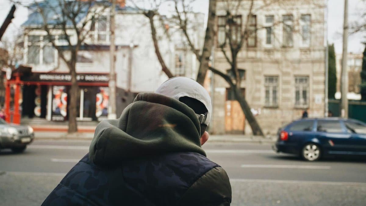 A man in a hoodie stands on a street in Ukraine, showcasing urban life.