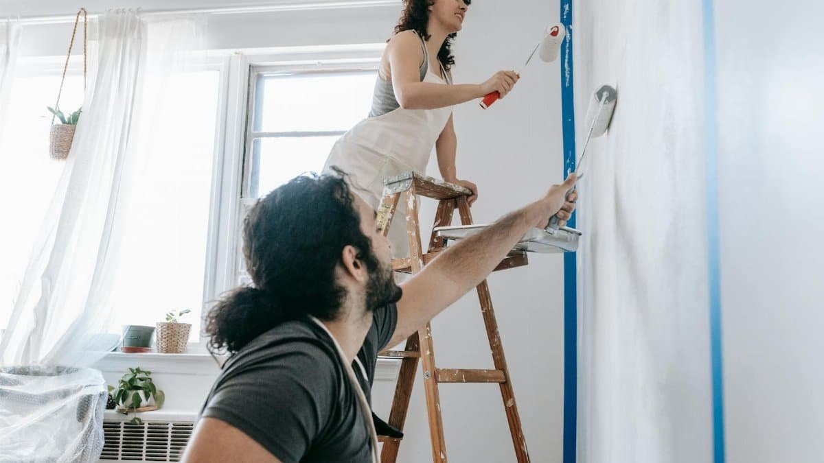 A couple engaged in a joyful home renovation, painting walls together.