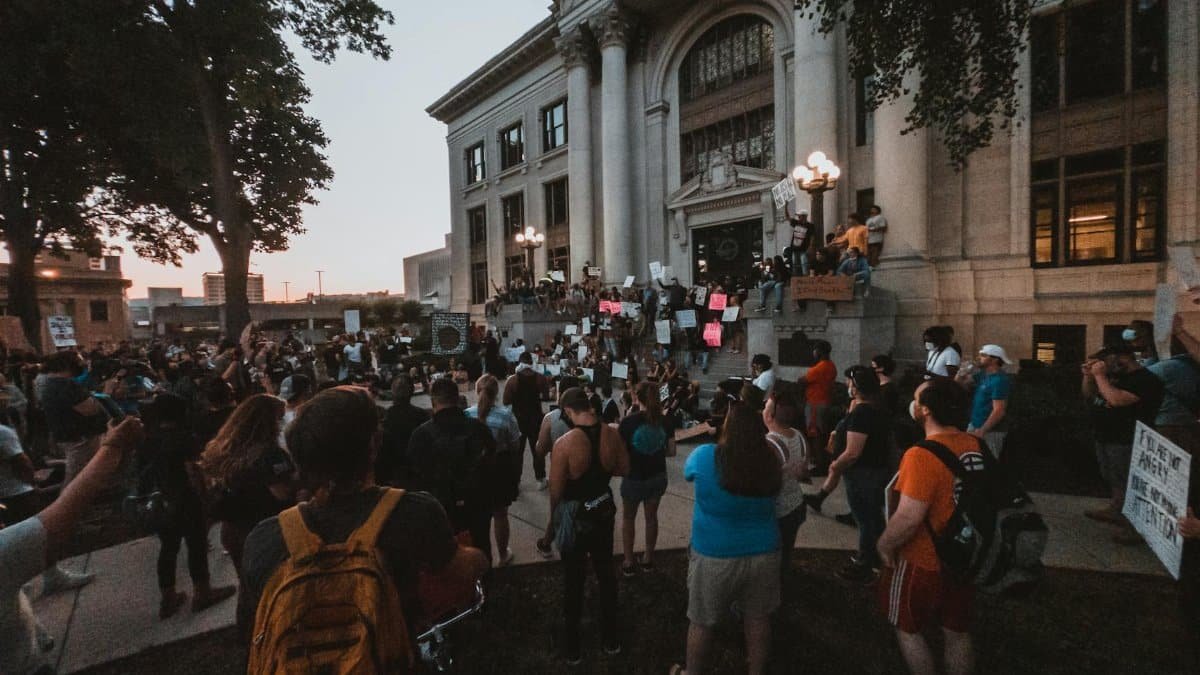 A large crowd gathers for a peaceful protest outside a historic building in Chattanooga at dusk.