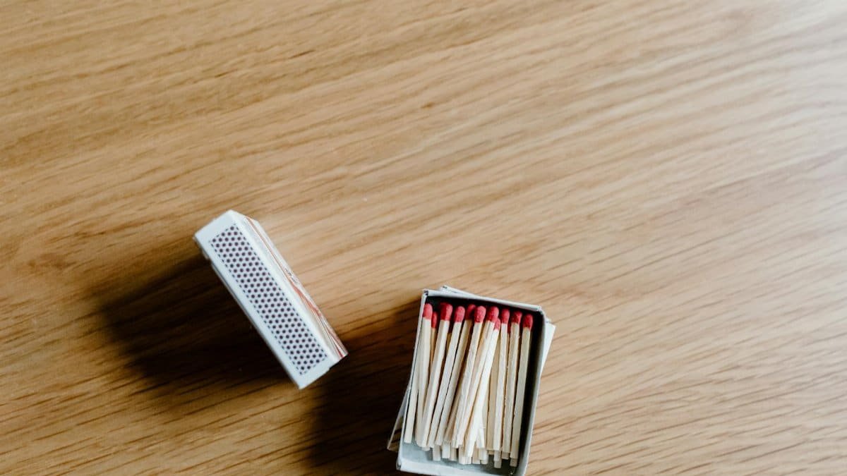 A close-up of an open matchbox with matchsticks on a wooden surface.