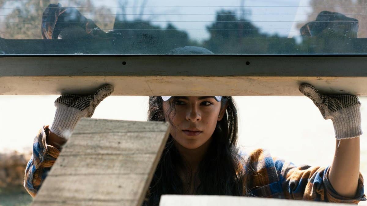 Young woman in gloves working on carpentry project, showcasing skills and determination.