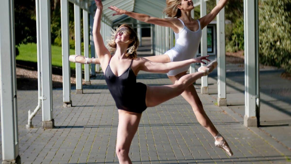 Two ballet dancers gracefully perform under a covered walkway in Seattle.