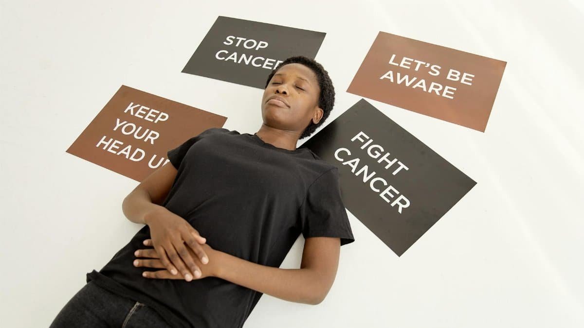 A person lying amidst motivational placards about cancer awareness and resilience.