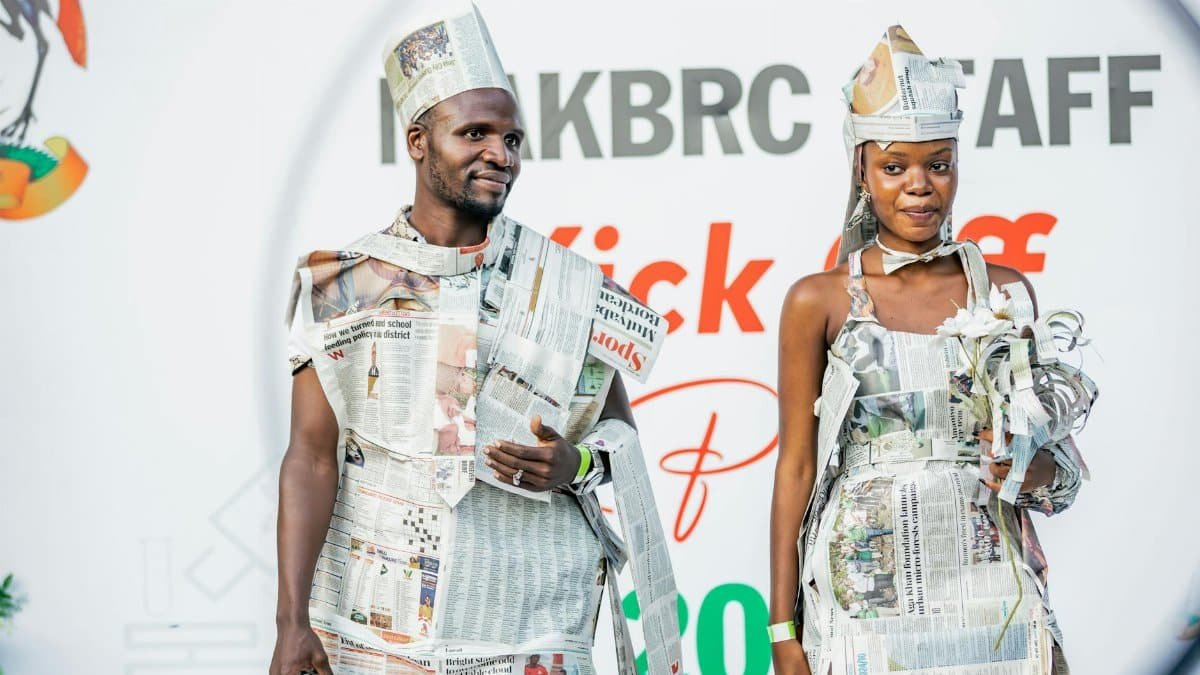 Two individuals in stylish newspaper outfits at a public event.
