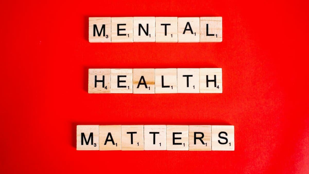 Wooden tiles spelling 'Mental Health Matters' on a vivid red background.