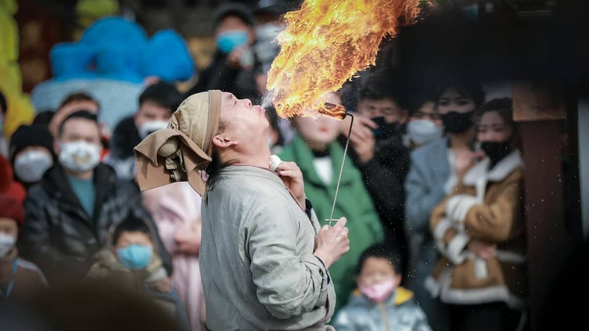 Fire performer entertains a crowd with fiery spectacle, capturing live audience reactions.
