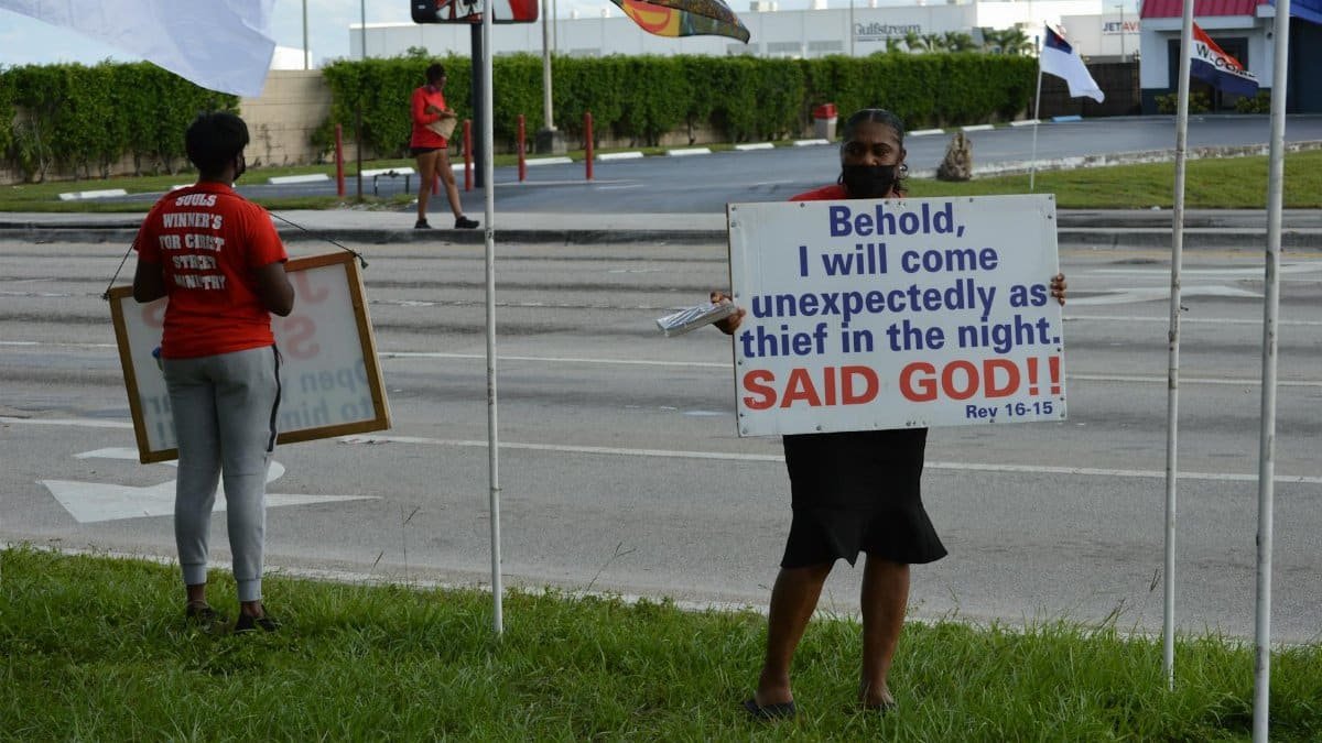 Two people holding religious signs on a street discussing Revelation 16:15.
