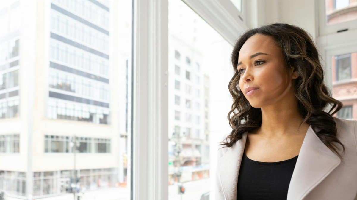 A pensive woman gazes out the window, capturing the essence of city life in Detroit.