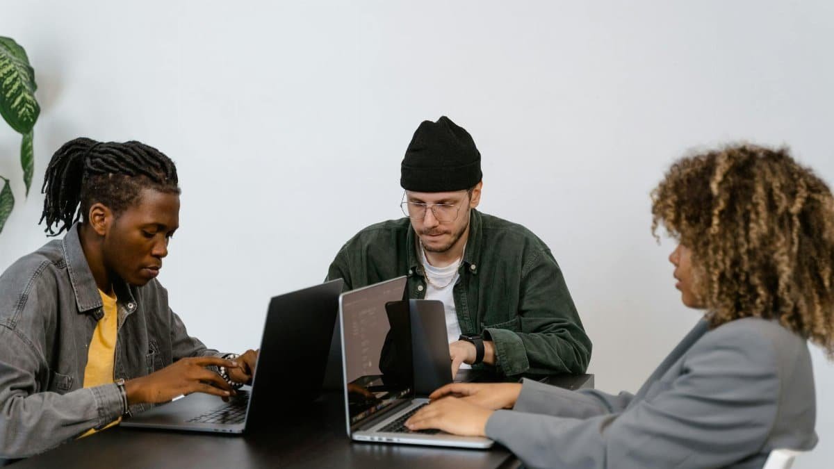 A diverse group of professionals working together on laptops in a contemporary office environment.