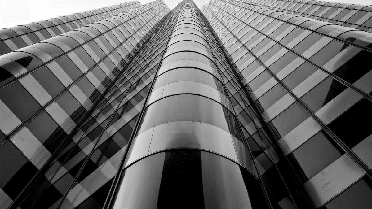 Low angle black and white view of a modern skyscraper in San Francisco, highlighting glass reflections.