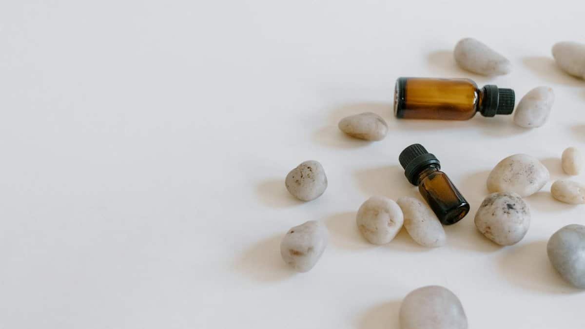 Minimalist arrangement of essential oil bottles surrounded by stones on a light background.