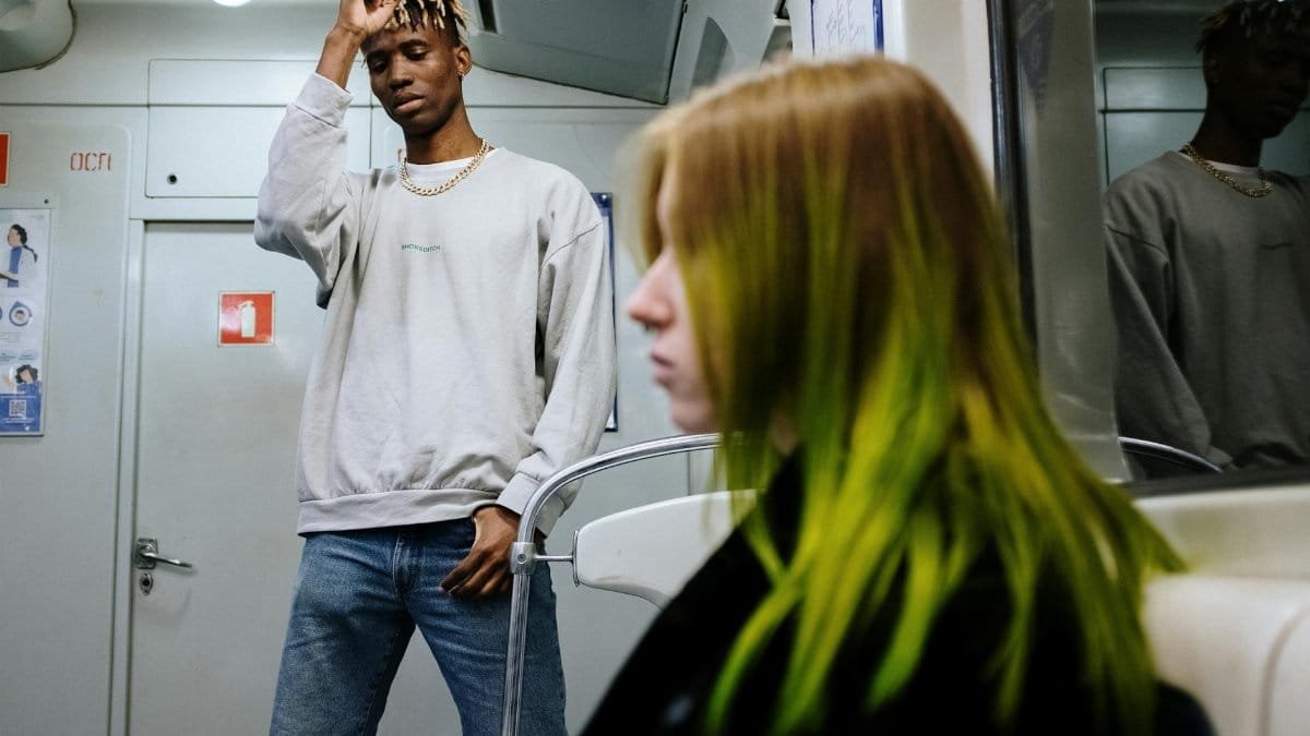A young man and woman with colorful hair ride an urban subway, showcasing modern urban life.