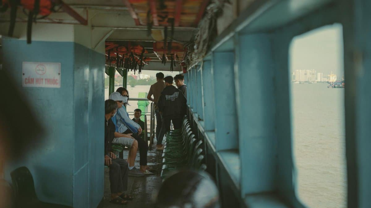 People onboard a ferry crossing the river in Ho Chi Minh City, capturing urban life in Vietnam.