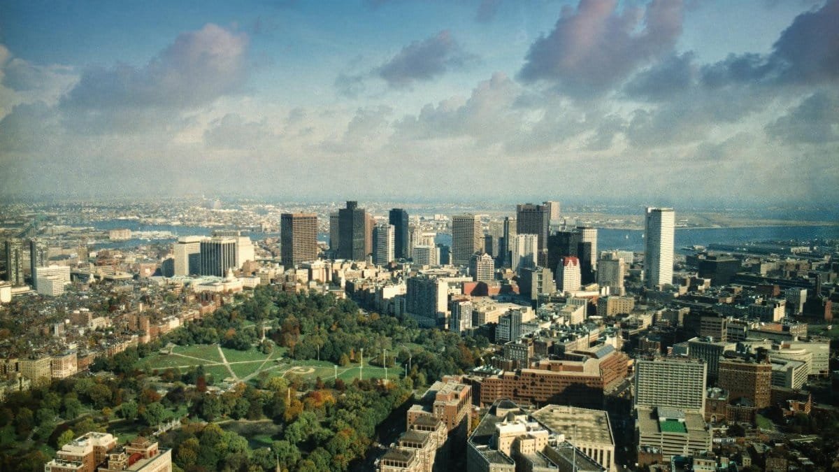 Aerial view showcasing the Boston skyline with lush parks and stunning clouds.