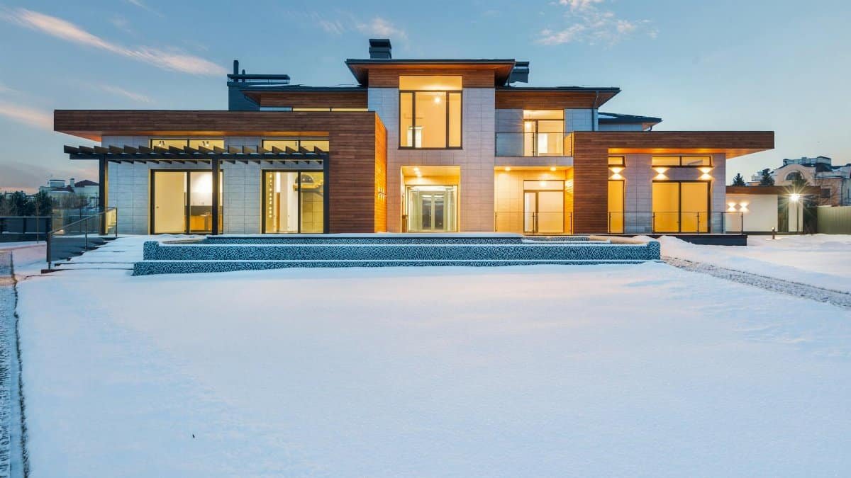 Contemporary luxury villa with modern design illuminated during winter with surrounding snow.