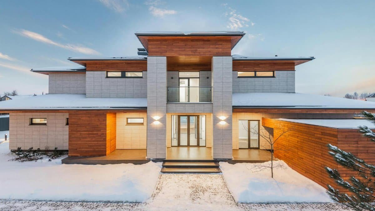 Backyard view of new modern luxurious cottage house with stone and wooden facade and illumination in winter countryside
