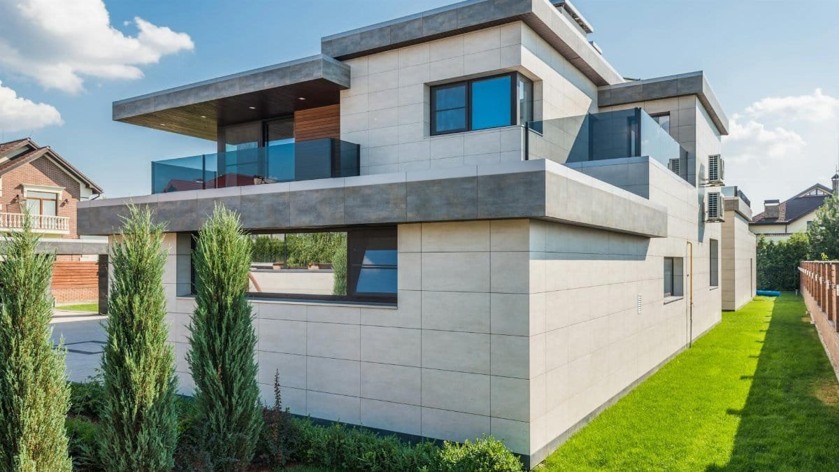 Contemporary two-story house with clean lines surrounded by green grass and blue sky.