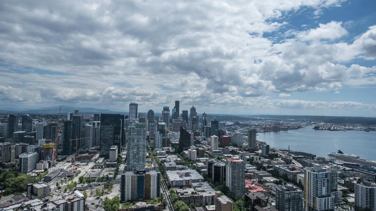 Aerial view of Seattle's skyline with Puget Sound in the background on a cloudy day.