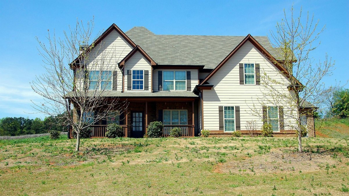 Beautiful two-story suburban home with a spacious lawn under clear blue skies.