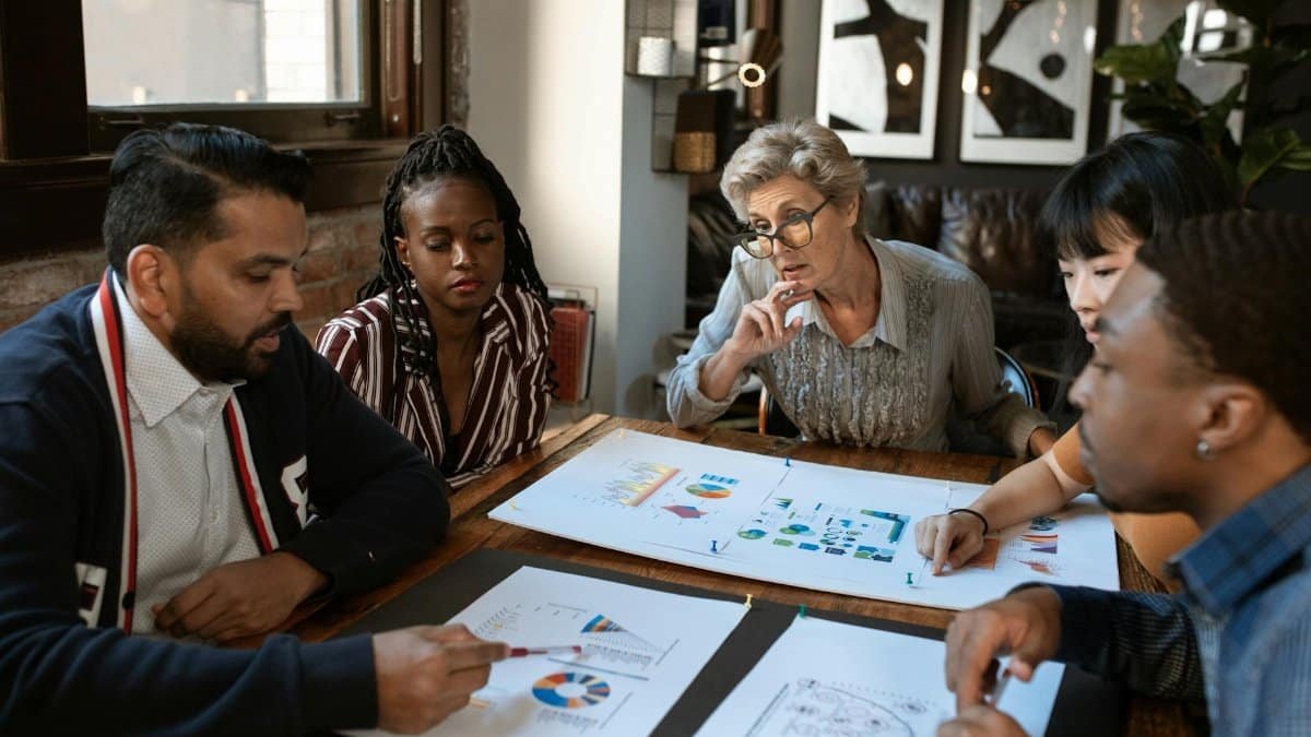 A multicultural team engaged in a business meeting with charts and graphs on the table.