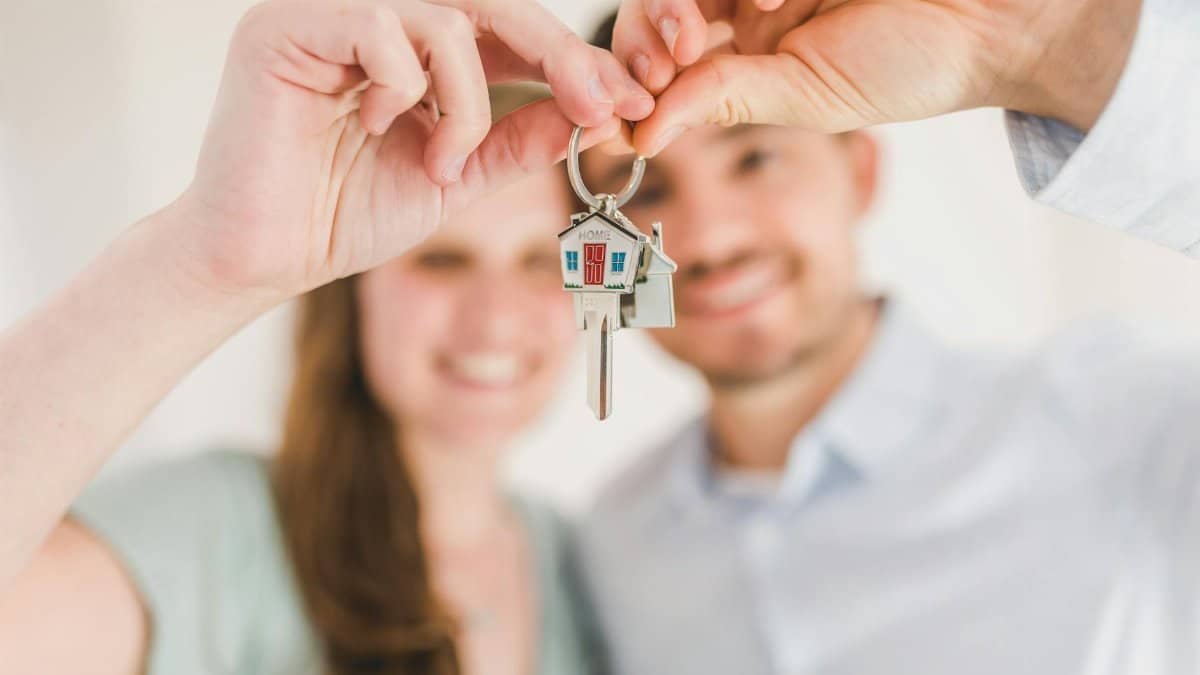 Young couple holding keys to their new home, symbolizing a fresh start and investment in real estate.