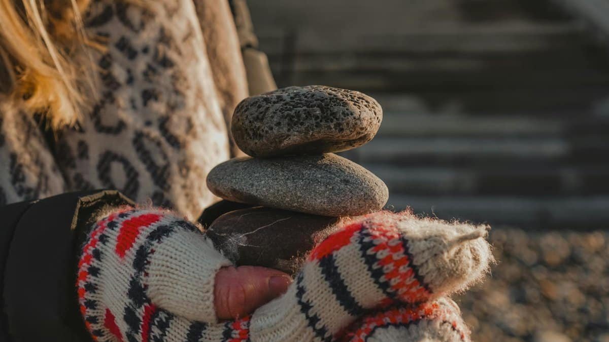 A warm winter moment capturing stacked pebbles held with cozy mittens outdoors.