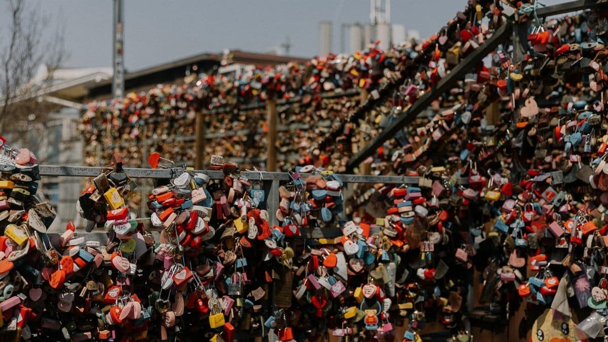 Colorful love locks densely covering a bridge railing in an urban setting, symbolizing commitment.