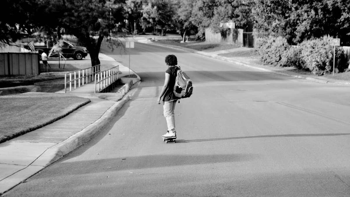 A teenager skating down a quiet street in a suburban neighborhood, San Antonio.