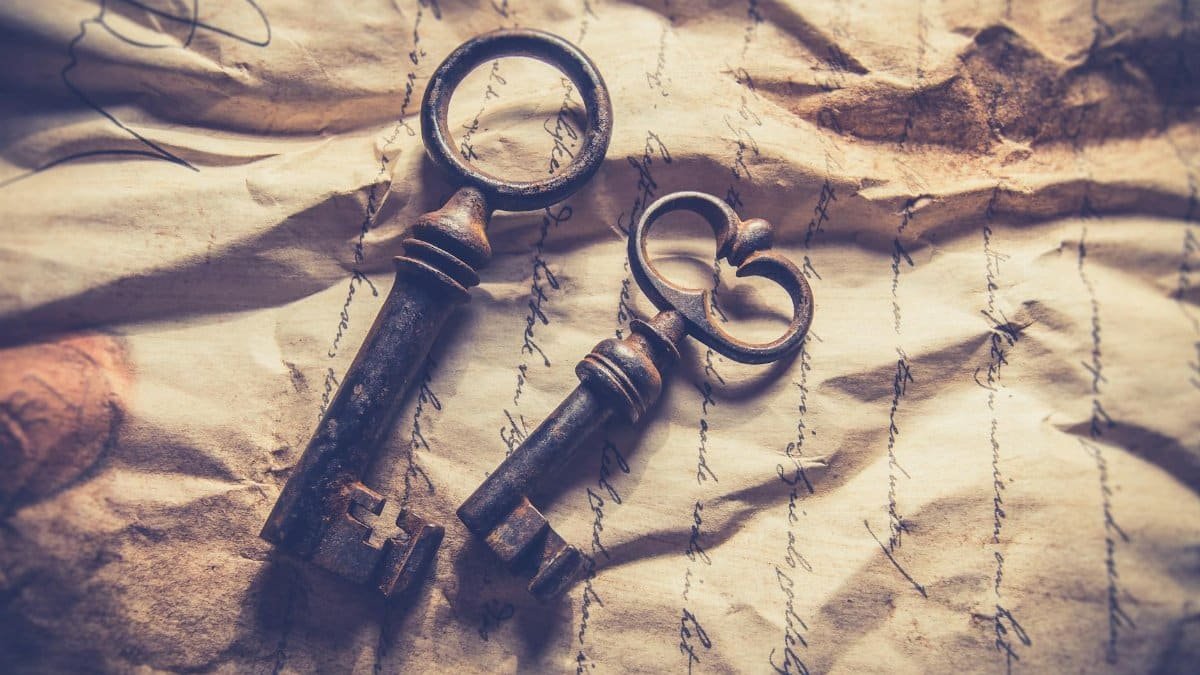 Vintage iron keys resting on crumpled, handwritten paper with a rustic texture.