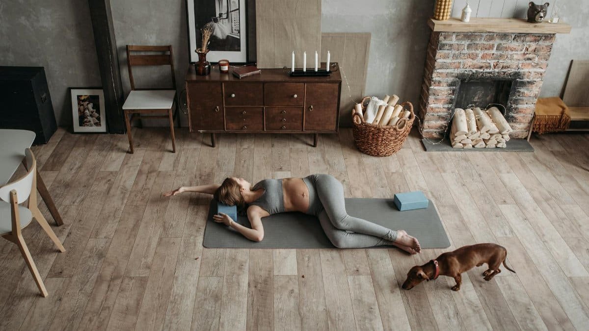 Pregnant woman doing yoga with her dachshund dog in cozy home environment, fostering relaxation.