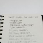 A notebook with handwritten ADHD symptoms like impatience and focus issues.