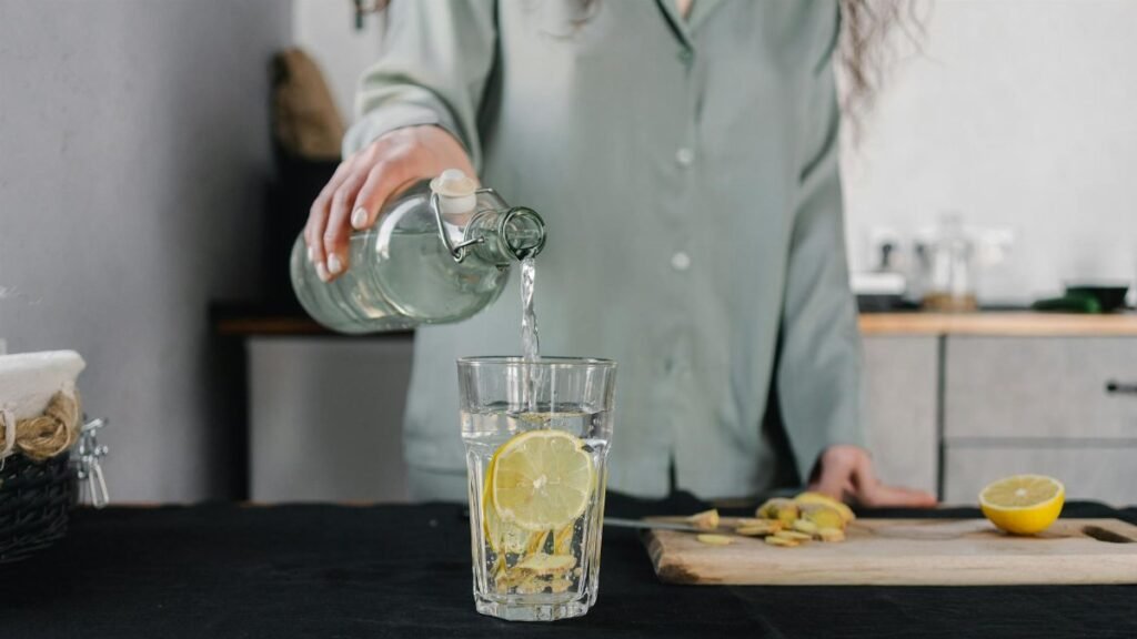 Woman pours water for lemon ginger infusion, promoting health and hydration.