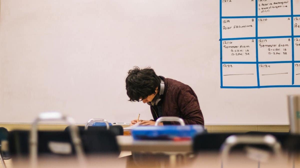 A high school student studying and solving problems in a classroom setting.