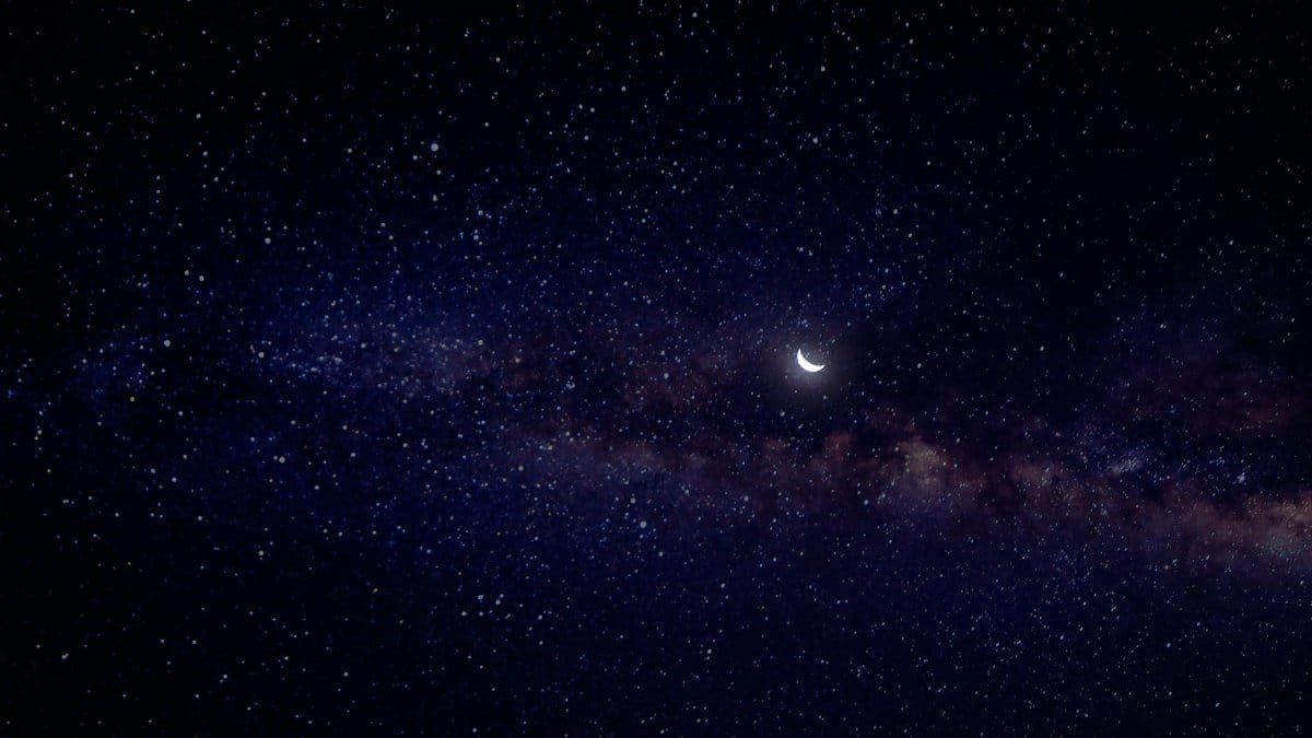 A serene view of a crescent moon nestled in a star-filled night sky with the Milky Way.
