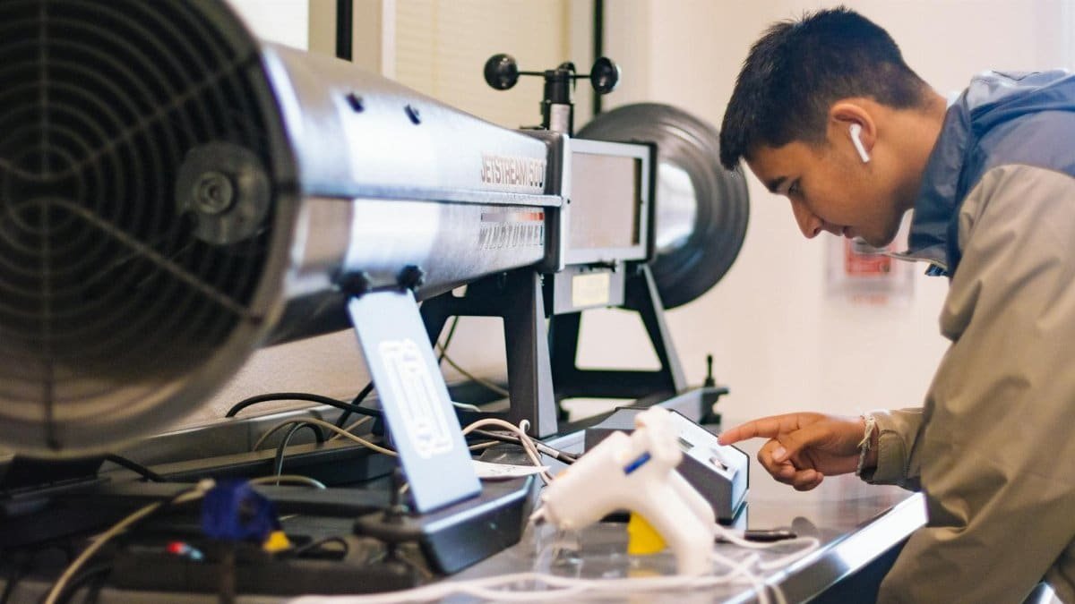 Young student interacts with jetstream apparatus in an engineering lab.