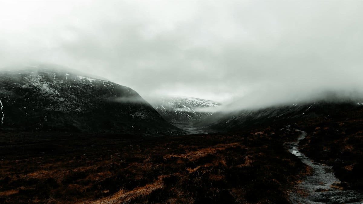 Majestic view of the misty Scottish Highlands with moody skies and rugged terrain.