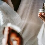 Woman in bathrobe applying skincare cream for a calm morning routine.