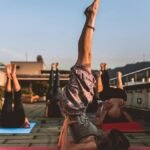 People practicing yoga on mats outdoors during sunset, focusing on wellness.