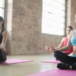 Women practicing yoga and meditation in a bright indoor studio setting.