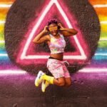 Vibrant image of a joyful woman jumping in front of a rainbow mural in Atlanta, Georgia.