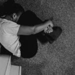 A moody black and white photo of a man sitting on stairs, deep in thought.