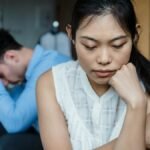 A couple experiencing relationship tension sitting silently on a sofa.