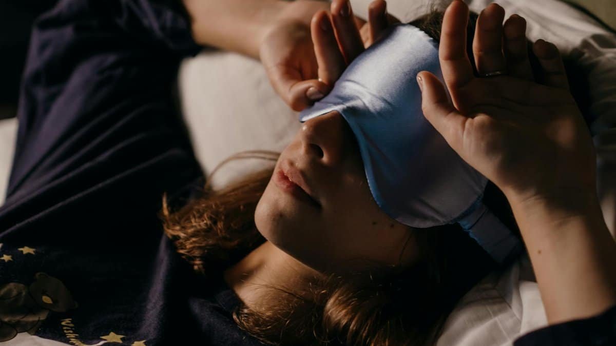 A woman resting at home wearing a sleep mask for a cozy afternoon nap.