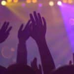 Silhouettes of a lively audience with raised hands at an energetic nightclub event.