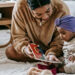 A mother and her baby bonding over a book on the floor of a cozy living room.